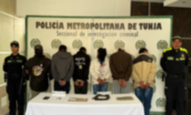 dos polic&iacute;as a los lados y en la mitad 6 personas capturadas con una mesa y elementos incautados