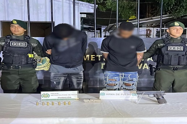 Dos Policías custodian a dos capturados y arma de fuego incautado