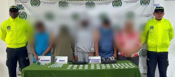 Dos policías al lado de cinco personas capturadas con estupefacientes