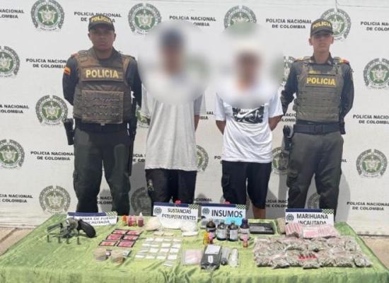 dos polic&iacute;as al lado de dos hombres capturados