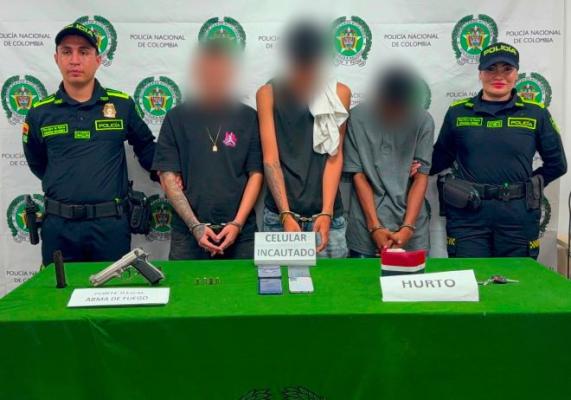 dos policías al lado de dos hombres capturados con material incautado