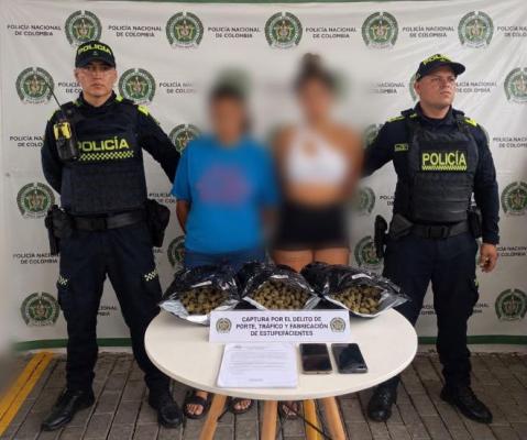 dos polic&iacute;as al lado de dos mujeres capturadas con estupefacientes