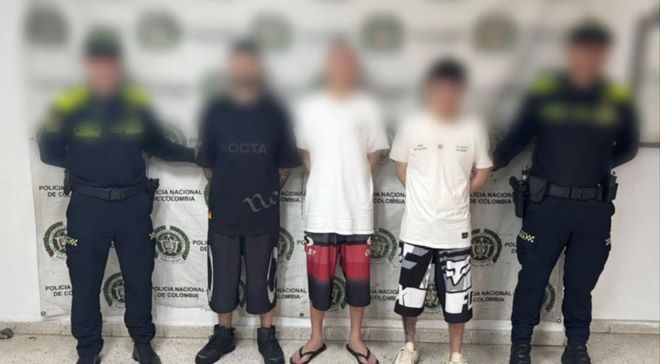 dos polic&iacute;as al lado de tres hombre capturados 