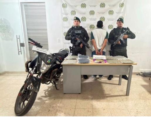 dos polic&iacute;as al lado de un hombre capturado con material incautado