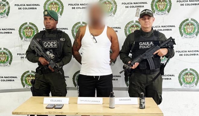 Dos policías al lado de un hombre capturado y elementos incautados encima de una mesa