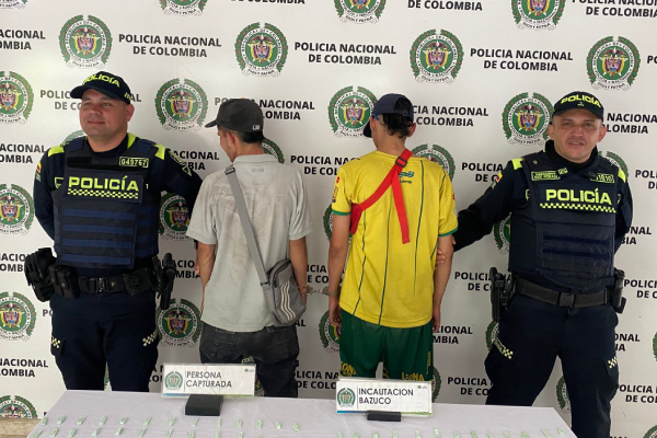 Dos hombres capturados, uno de camiseta gris y otro de camiseta amarilla en medio de dos policias