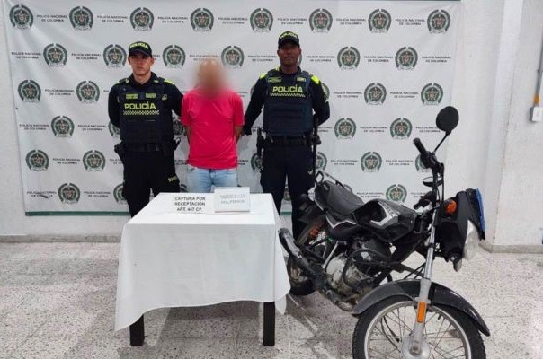 un capturado, dos policías que realizan la captura y una motocicleta