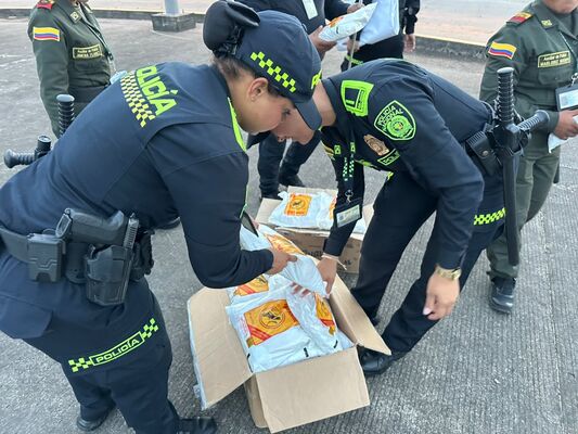 Funcionarios de la Policía de Colombia revisan y clasifican los paquetes incautados, abriendo las cajas para verificar su contenido, como parte del procedimiento oficial tras la operación que permitió el decomiso de mercancía ilegal