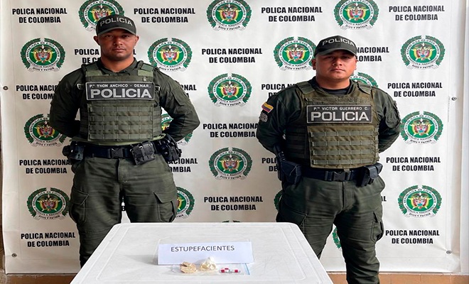 Dos Policías y en una mesa con sustancia estupefaciente incautada 