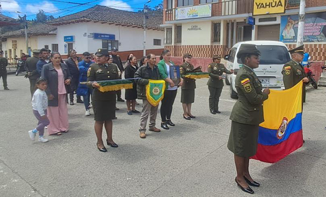 Policias y población desfilando con bandera de Colombia
