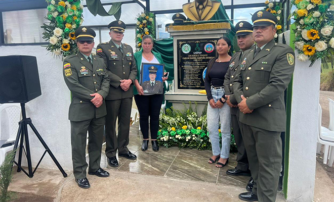 cuatro policias y dos familiares al lado de una placa conmemorativa