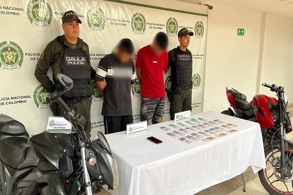 Dos policías junto a dos capturados, motocicletas, dinero y un celular incautados