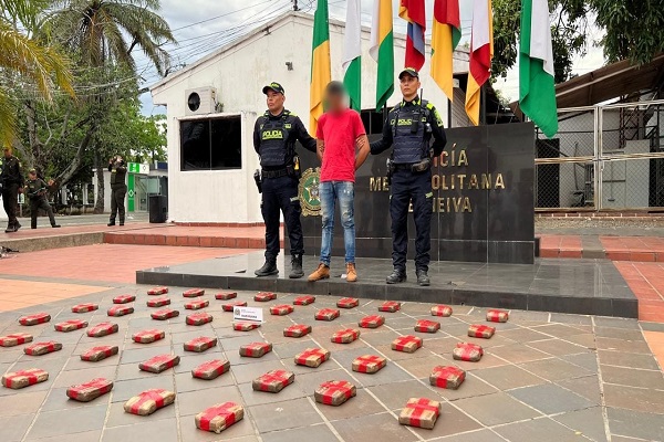 Dos polic&iacute;as junto a un capturado y 50 paquetes de marihuana incautados
