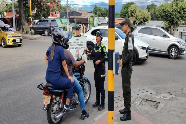 Tres uniformados realizan una campaña preventiva sobre la mendicidad infantil a dos ciudadanos que se movilizan en motocicleta