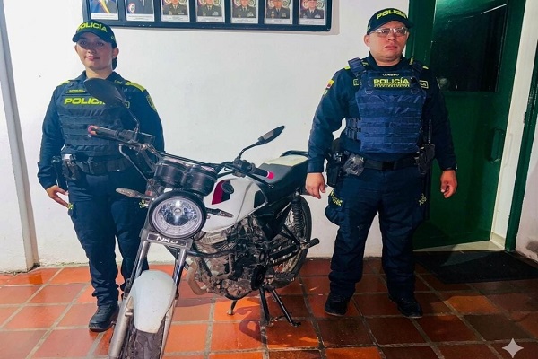 Dos policías junto a una motocicleta recuperada