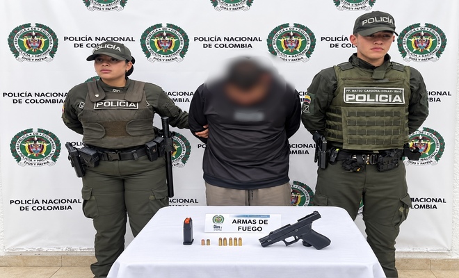 Un ciudadano capturado, esposado y con dos uniformados de la Polic&iacute;a en cada lado, as&iacute; como un arma de fuego incautada