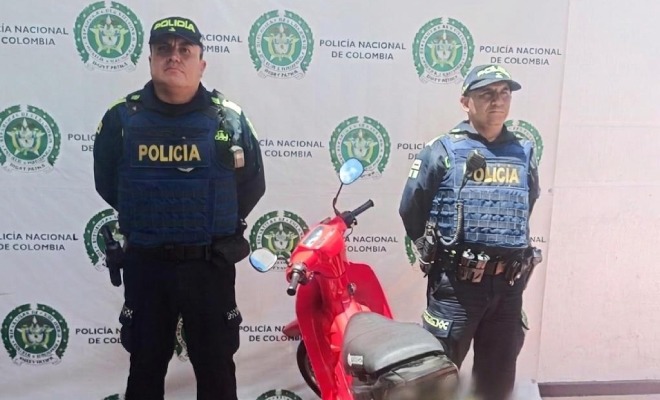 Dos policías, en el medio una motocicleta recuperada
