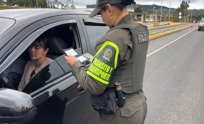 Una uniformada d ela Policía Nacional revisando la documentación d eun vehículo en la via 