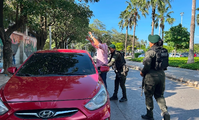 Un veh&iacute;culo rojo se encuentra detenido en una v&iacute;a, mientras varios uniformados realizan labores de seguridad y control