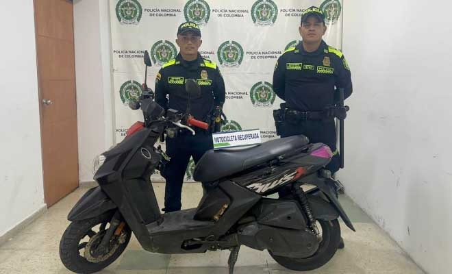 Dos policías, en frente motocicleta recuperada